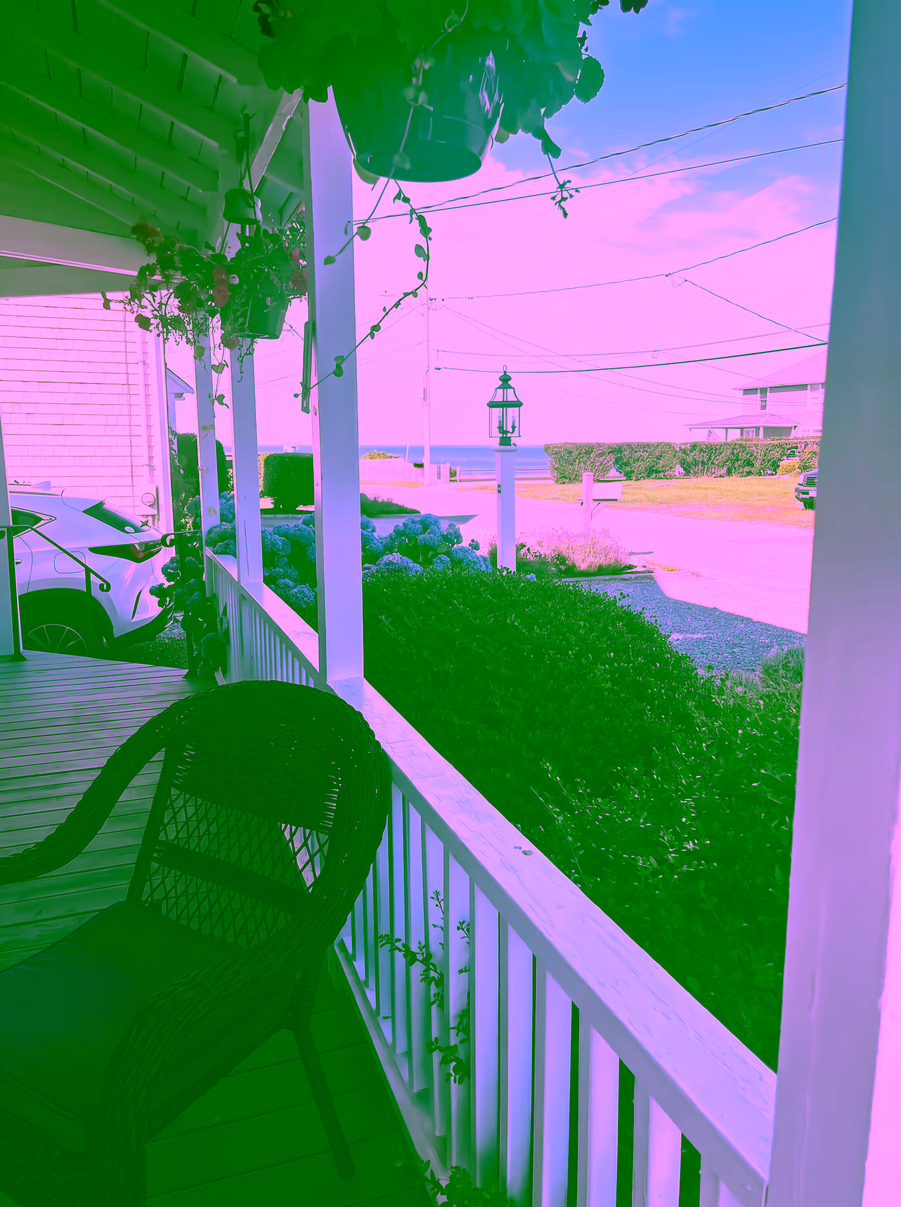 On the front porch past a wicker chair, looking toward the ocean