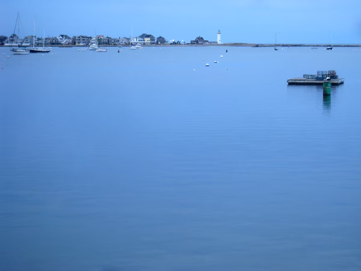 Scituate Harbor at dusk, boats on their moorings and Front Street along the water