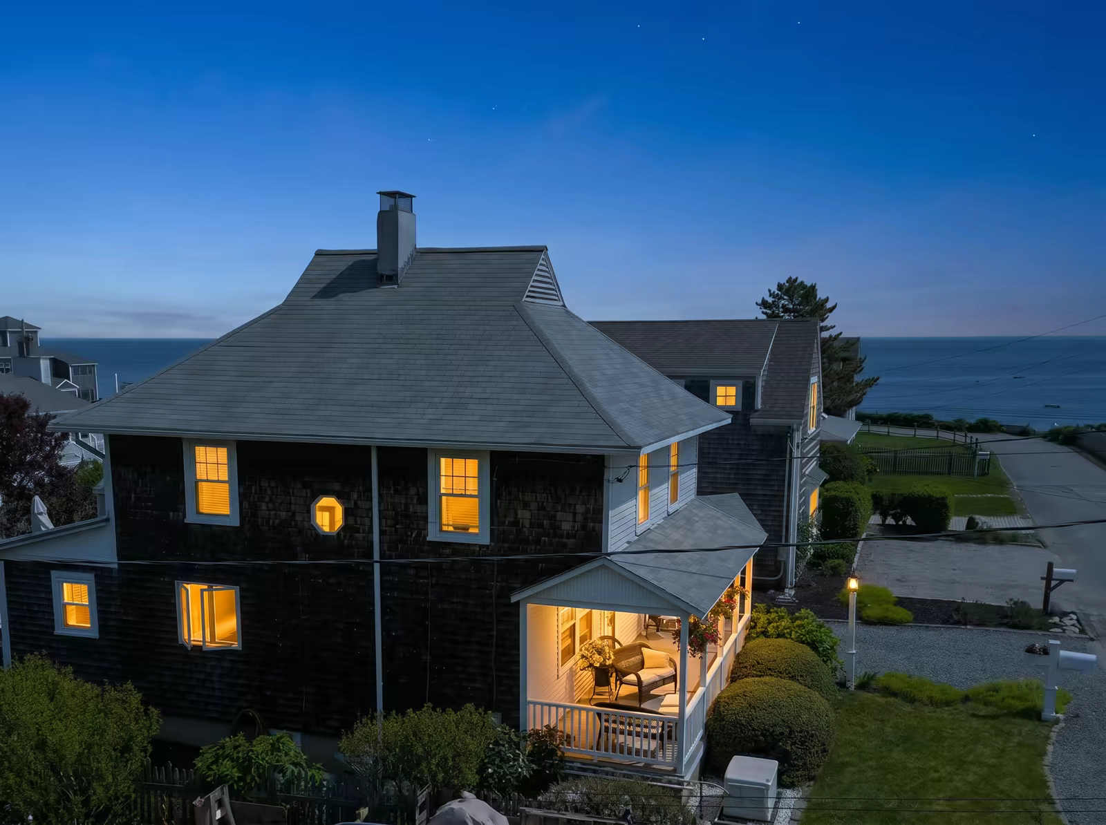 The house at blue hour with warm light glowing from every window