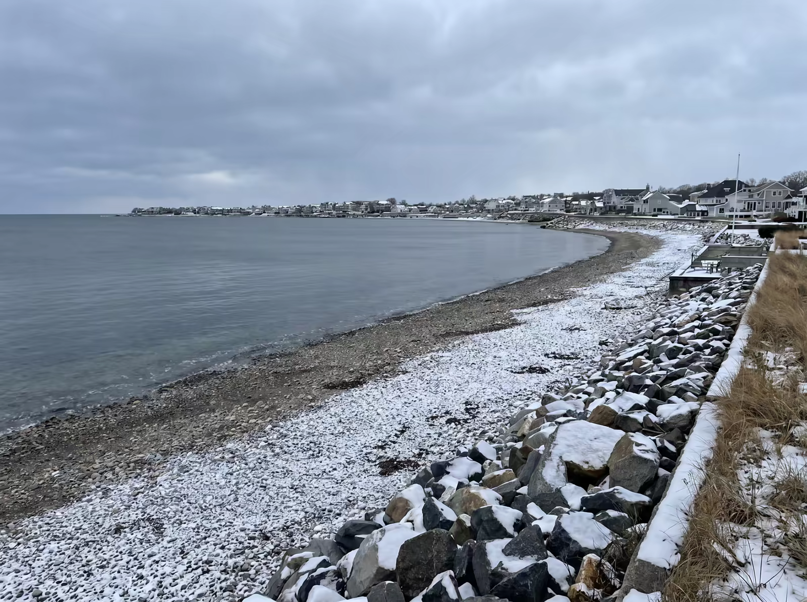 The beach in winter with snow dusting the rocks and a steel-gray sea