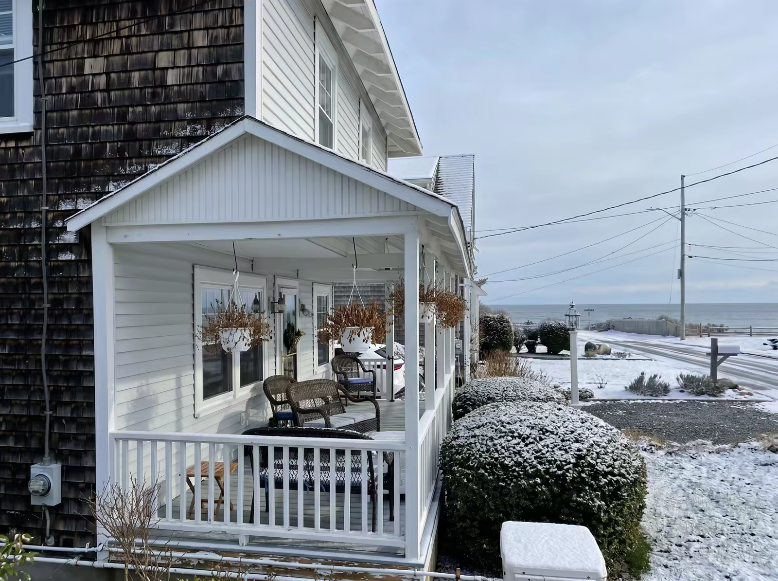 The porch after a light January snowfall, the ocean gray behind it